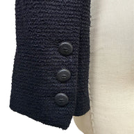 Close-up of engraved Chanel CC buttons at the sleeve cuff of the Spring Summer 2005 runway bouclé tuxedo jacket.