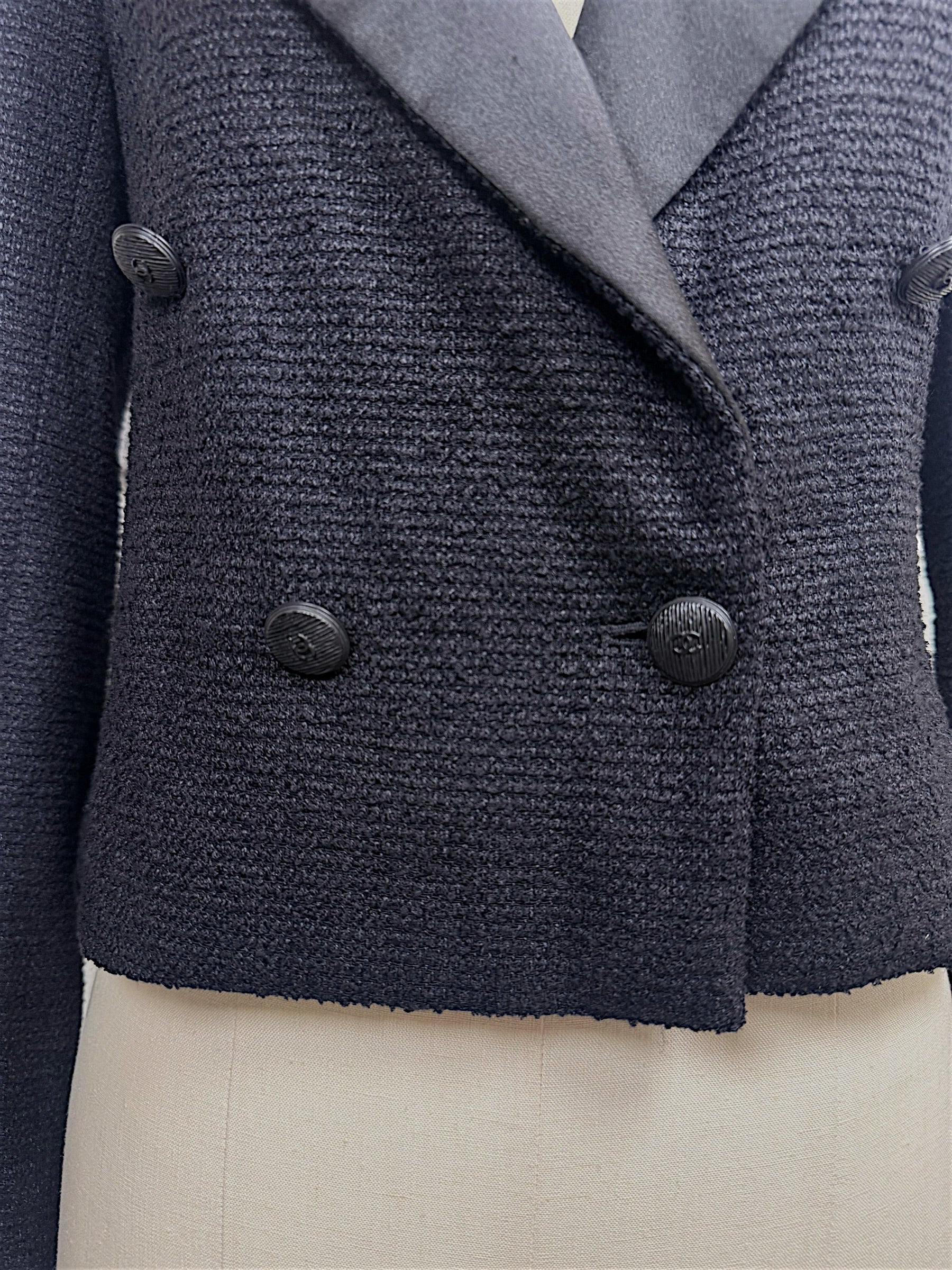 Close-up of the double-breasted front with engraved tonal CC buttons on Chanel Spring 2005 runway cropped tuxedo jacket.