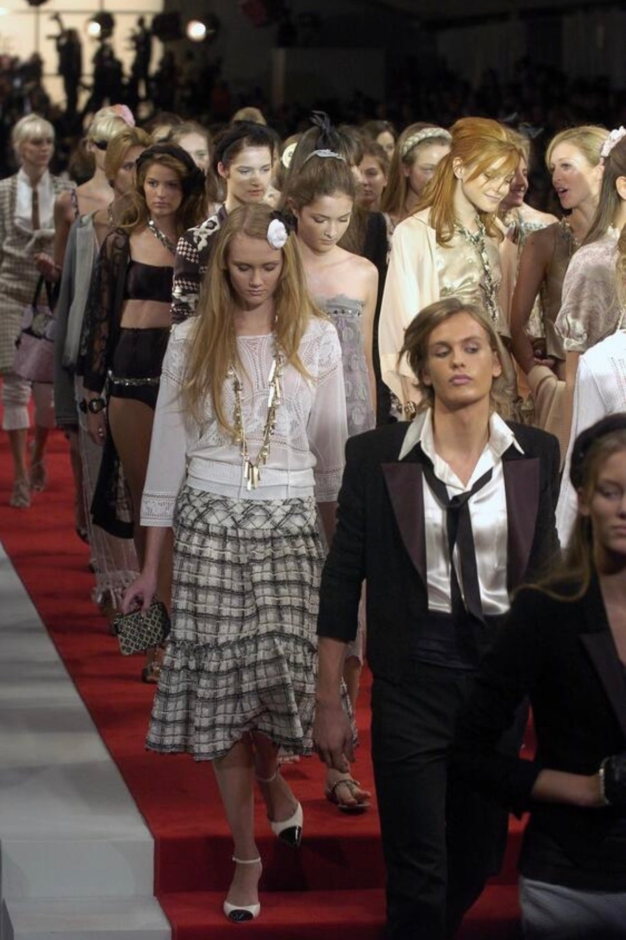 Runway finale photograph from Chanel Spring Summer 2005 featuring the documented cropped black bouclé tuxedo jacket among the collection presentation.
