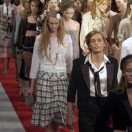 Runway finale photograph from Chanel Spring Summer 2005 featuring the documented cropped black bouclé tuxedo jacket among the collection presentation.