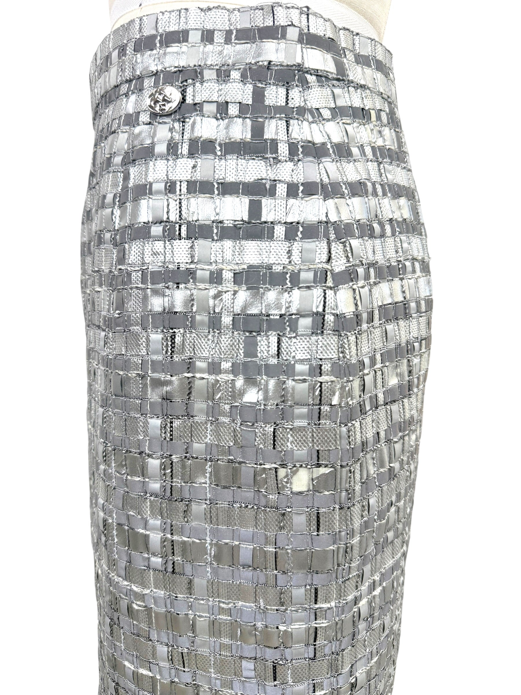 Detail of small mid hip area with missing metallic material on Chanel silver woven skirt.