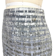 Close view of Chanel Spring 2016 silver metallic woven skirt waistband and logo button.