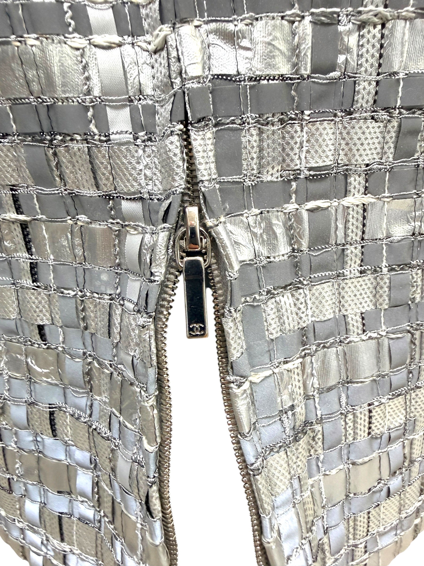 Close view of Chanel CC zipper pull on silver metallic woven pencil skirt.