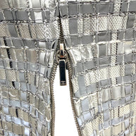 Close view of Chanel CC zipper pull on silver metallic woven pencil skirt.