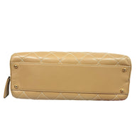 Bottom base of Chanel Surpique Bowler bag with protective gold feet and beige lambskin leather construction.