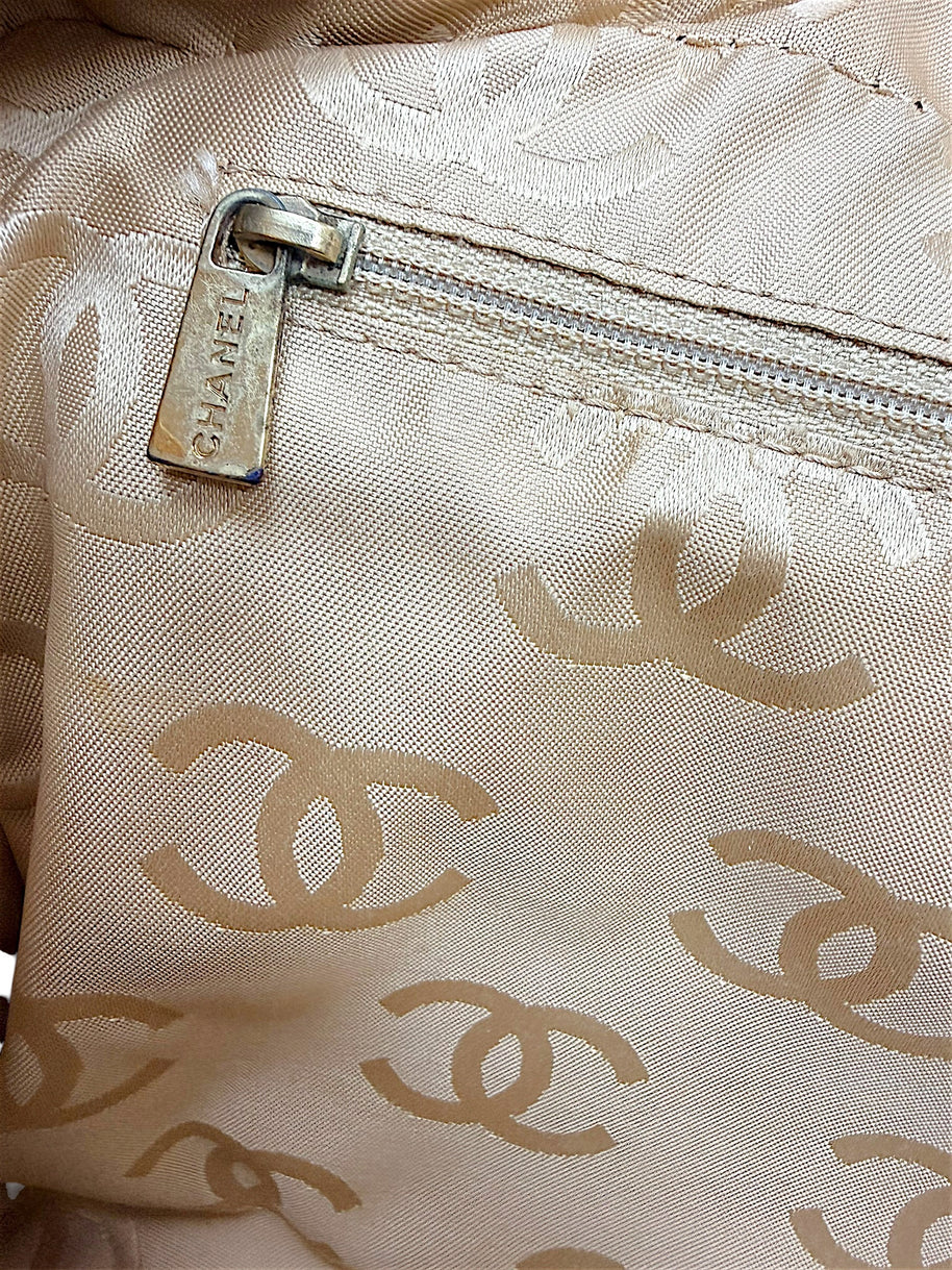 Interior zipper pocket detail with Chanel engraved pull and beige CC jacquard lining.