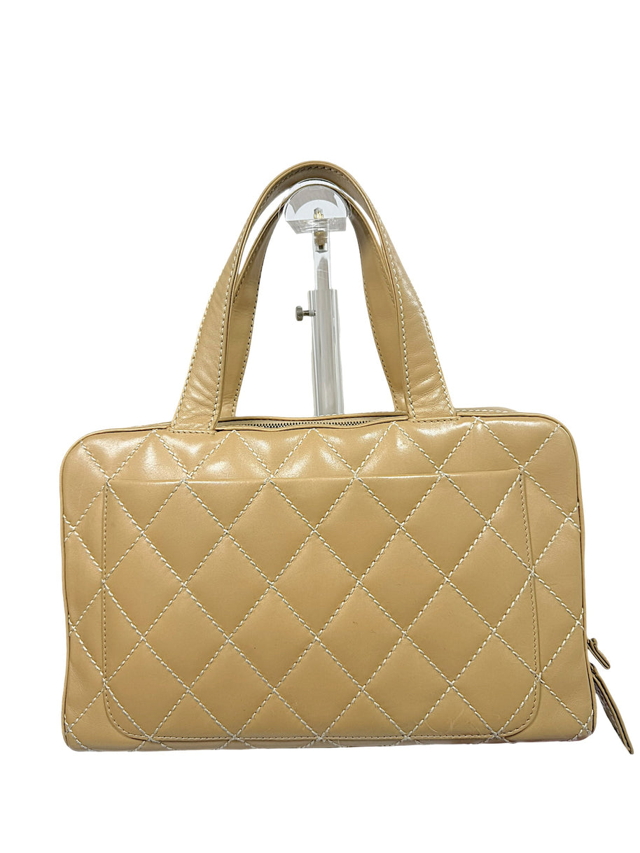 Rear exterior view of Chanel Surpique Bowler bag showing oversized quilting and rolled leather handles.