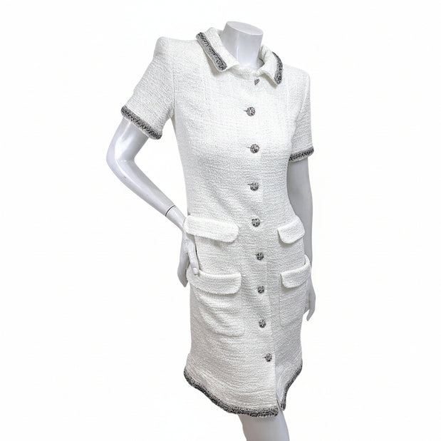 Angled front view of Chanel white bouclé tweed short sleeve dress with silver metallic trim and front pockets