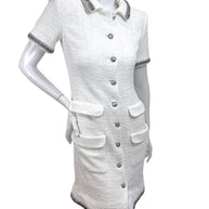 Angled front view of Chanel white bouclé tweed short sleeve dress with silver metallic trim and front pockets
