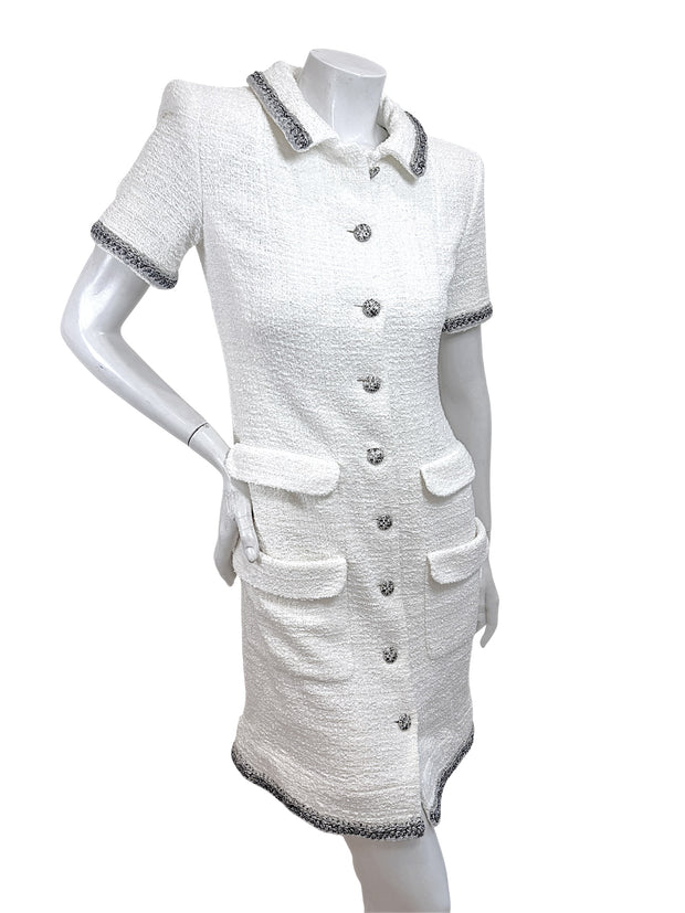 Angled front view of Chanel white bouclé tweed short sleeve dress with silver metallic trim and front pockets