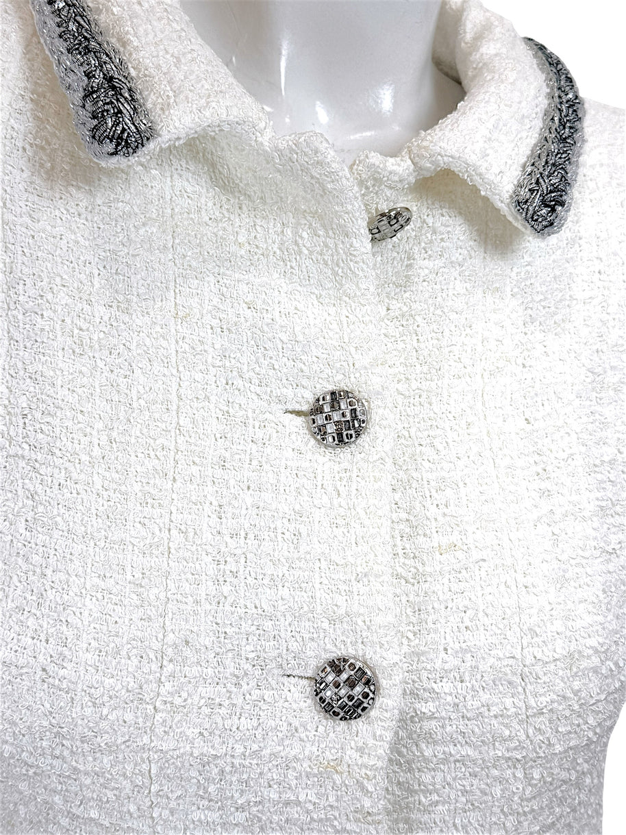 Close-up of Chanel white bouclé tweed dress featuring signature logo buttons and metallic trim collar detail