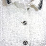 Close-up of Chanel white bouclé tweed dress featuring signature logo buttons and metallic trim collar detail