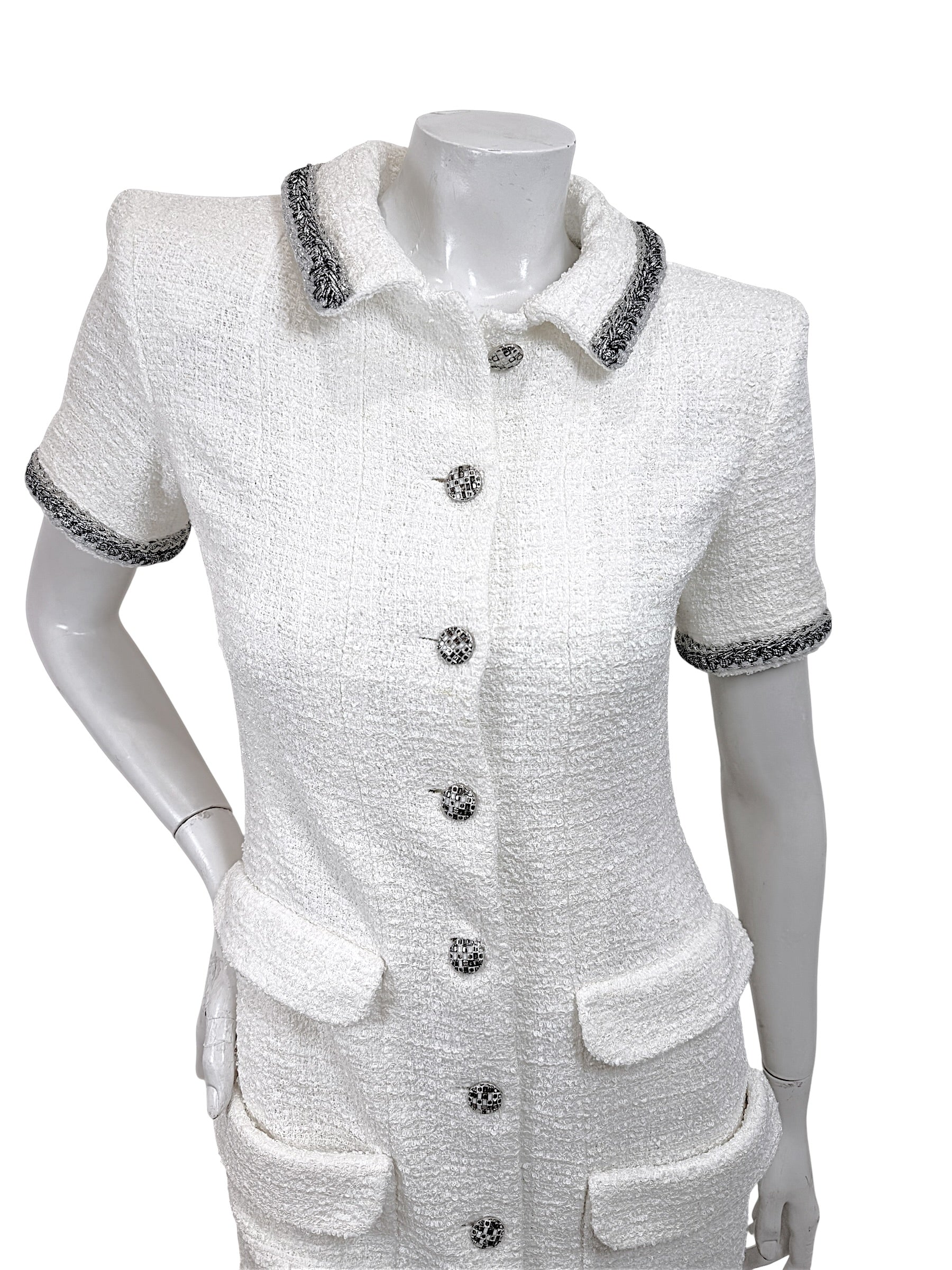 Upper front detail of Chanel white bouclé tweed dress featuring metallic trim collar and jeweled logo buttons