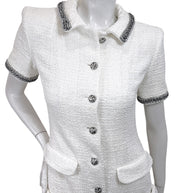 Upper front detail of Chanel white bouclé tweed dress featuring metallic trim collar and jeweled logo buttons
