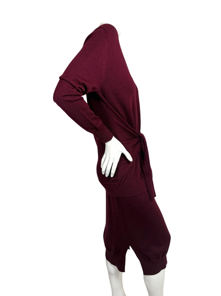 Side profile of Chloé burgundy wool layered-effect sweater dress showing relaxed long-sleeve silhouette, waist tie and midi skirt side slit.