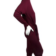 Side profile of Chloé burgundy wool layered-effect sweater dress showing relaxed long-sleeve silhouette, waist tie and midi skirt side slit.