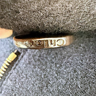 Detail of engraved Chloé button on authentic black wool cropped cape jacket