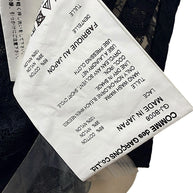 Close-up of Comme des Garçons black sheer floral lace shirt fabric composition and care label, showing 65% cotton, 35% nylon, Made in Japan and style GJ-B008.