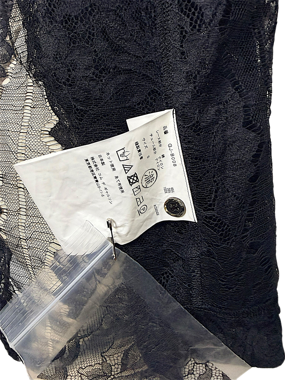 Close-up of Japanese Comme des Garçons shirt care label with style code GJ-B008 and 65 percent cotton, 35 percent nylon composition.