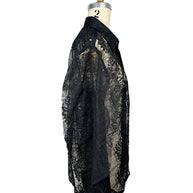 Side profile of Comme des Garçons sheer black floral lace shirt showing relaxed silhouette, transparent sleeves and curved hem.