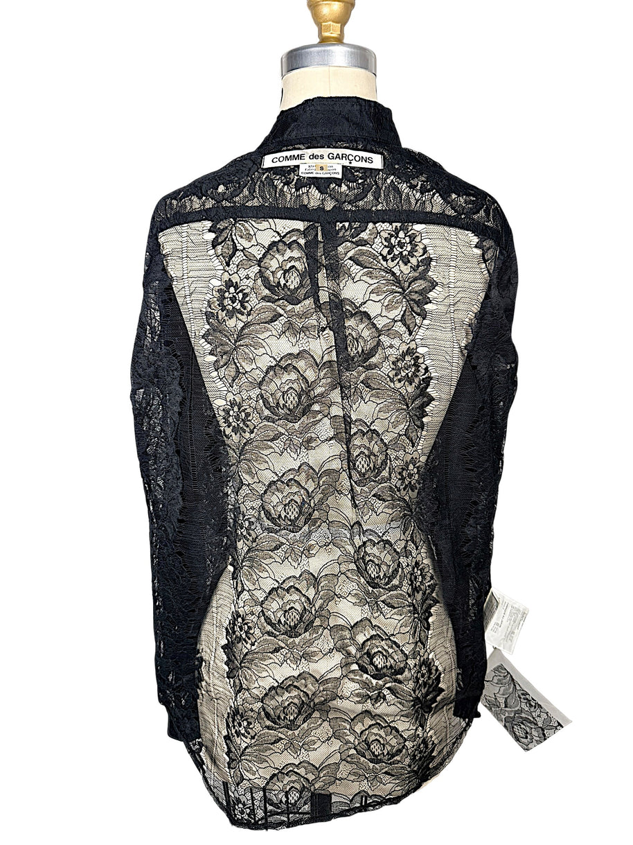 Back of Comme des Garçons black sheer floral lace shirt on dress form, showing floral pattern, collar and original designer label.