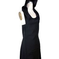 Angled front view of Courrèges Fall 2024 Look 23 black Oblique Space mini dress with oversized hood raised and architectural fitted silhouette.