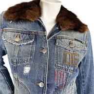 Close-up of Dolce & Gabbana vintage denim jacket showing brown fur collar, flap chest pockets, silver-tone logo buttons, and embroidered 05 detail.