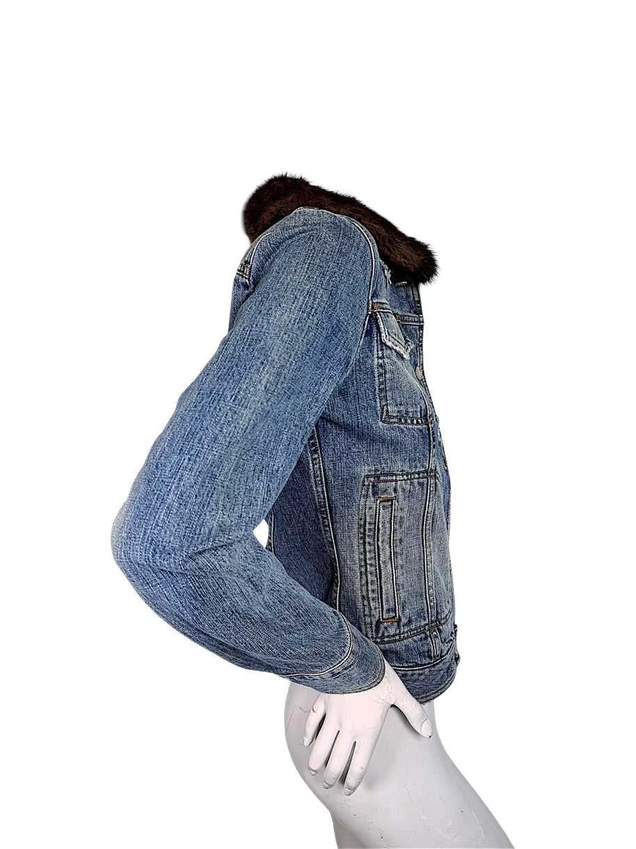 Side profile of vintage Dolce & Gabbana blue denim jacket showing contoured waist seams, long sleeves, buttoned cuff, and brown fur collar.
