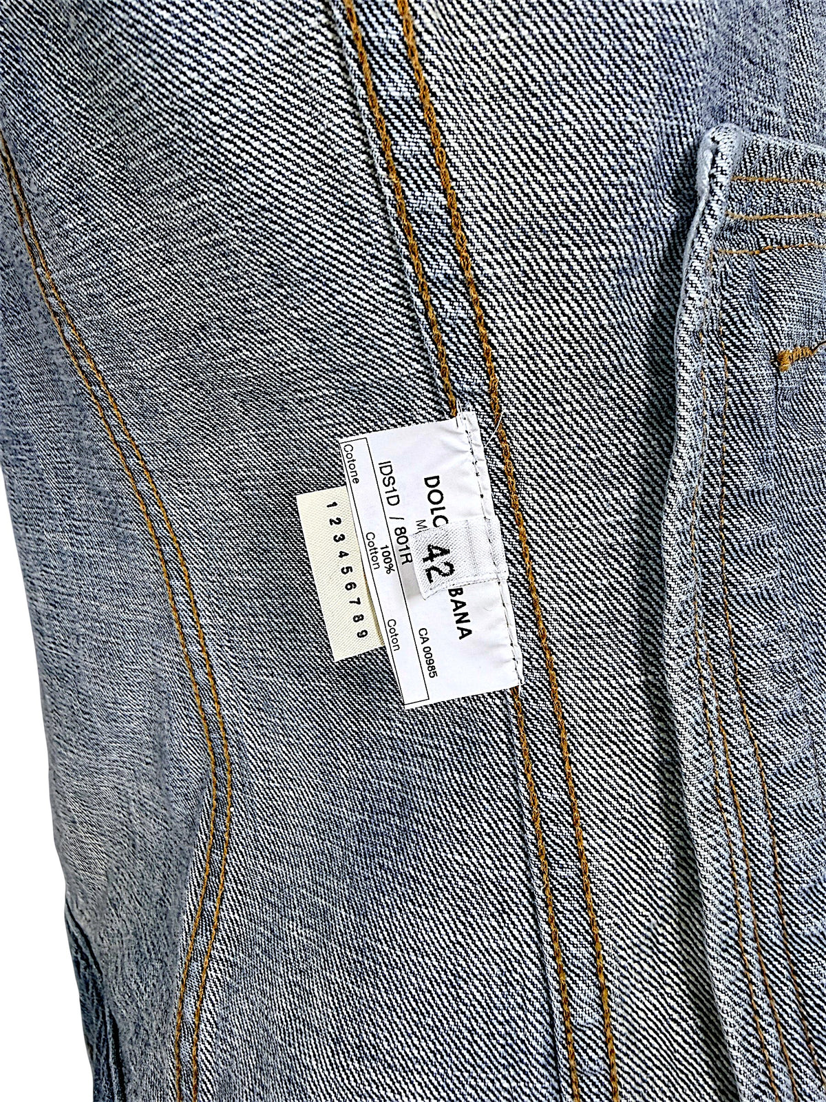 Interior Dolce & Gabbana vintage denim jacket label showing Italian size 42, 100% cotton composition, style reference, and contrast-stitched denim seams.