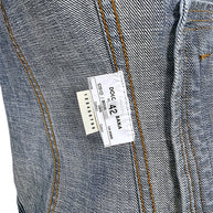 Interior Dolce & Gabbana vintage denim jacket label showing Italian size 42, 100% cotton composition, style reference, and contrast-stitched denim seams.