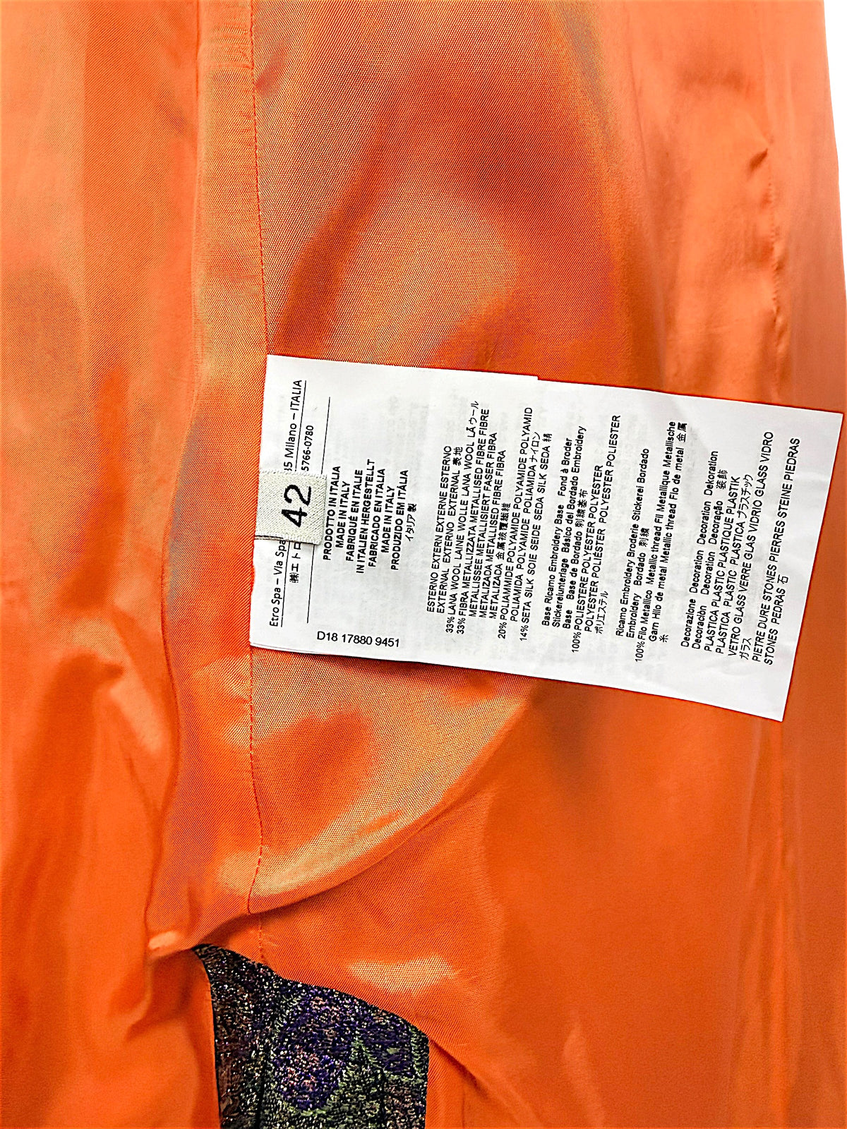 Etro metallic paisley jacquard longline vest interior composition and care label showing Italian size 42, wool-blend fabric content, and Made in Italy details against orange lining.