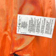 Etro metallic paisley jacquard longline vest interior composition and care label showing Italian size 42, wool-blend fabric content, and Made in Italy details against orange lining.