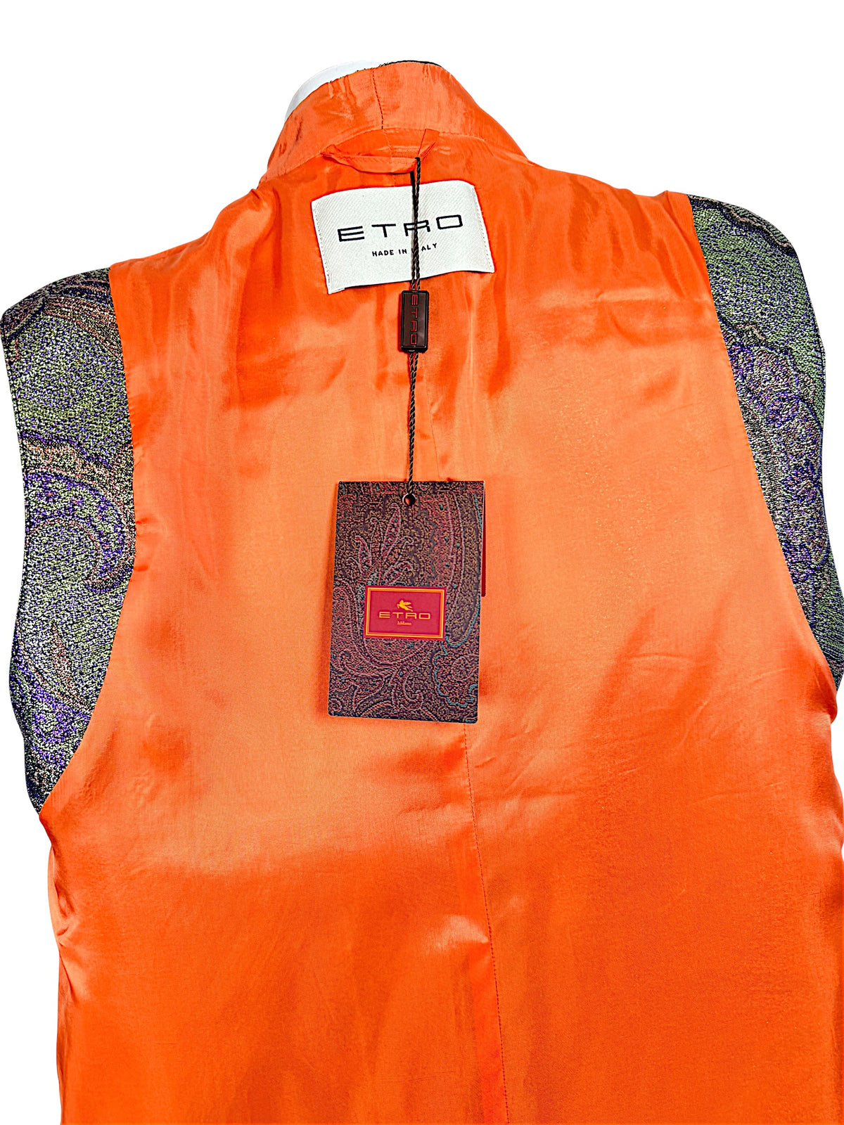 Close-up of Etro Made in Italy designer label and original paisley-patterned retail hangtag against bright orange vest lining.