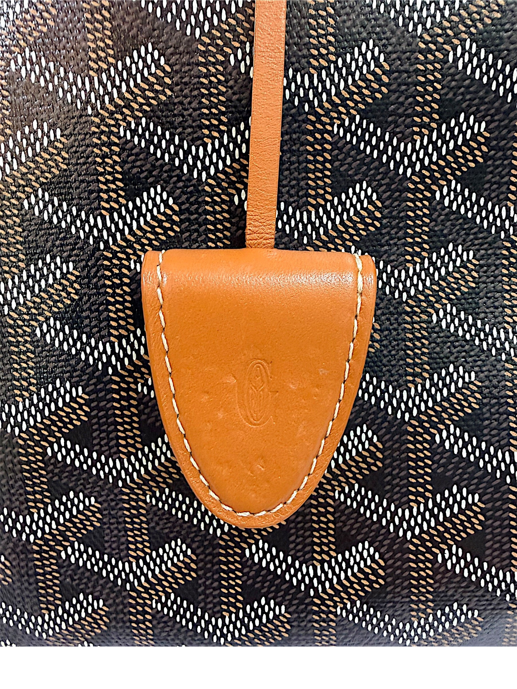 Close-up of Goyard Artois PM leather clochette showing natural indentations and wear consistent with use.