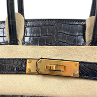 Close-up detail of Hermès Birkin gold hardware turnlock on black crocodile leather