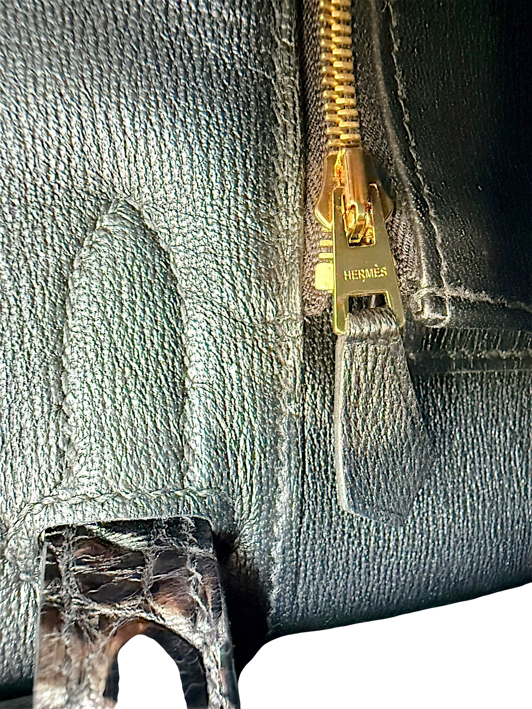 Close-up detail of Hermès branded gold zipper pull inside black crocodile Birkin 30 handbag