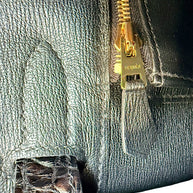 Close-up detail of Hermès branded gold zipper pull inside black crocodile Birkin 30 handbag
