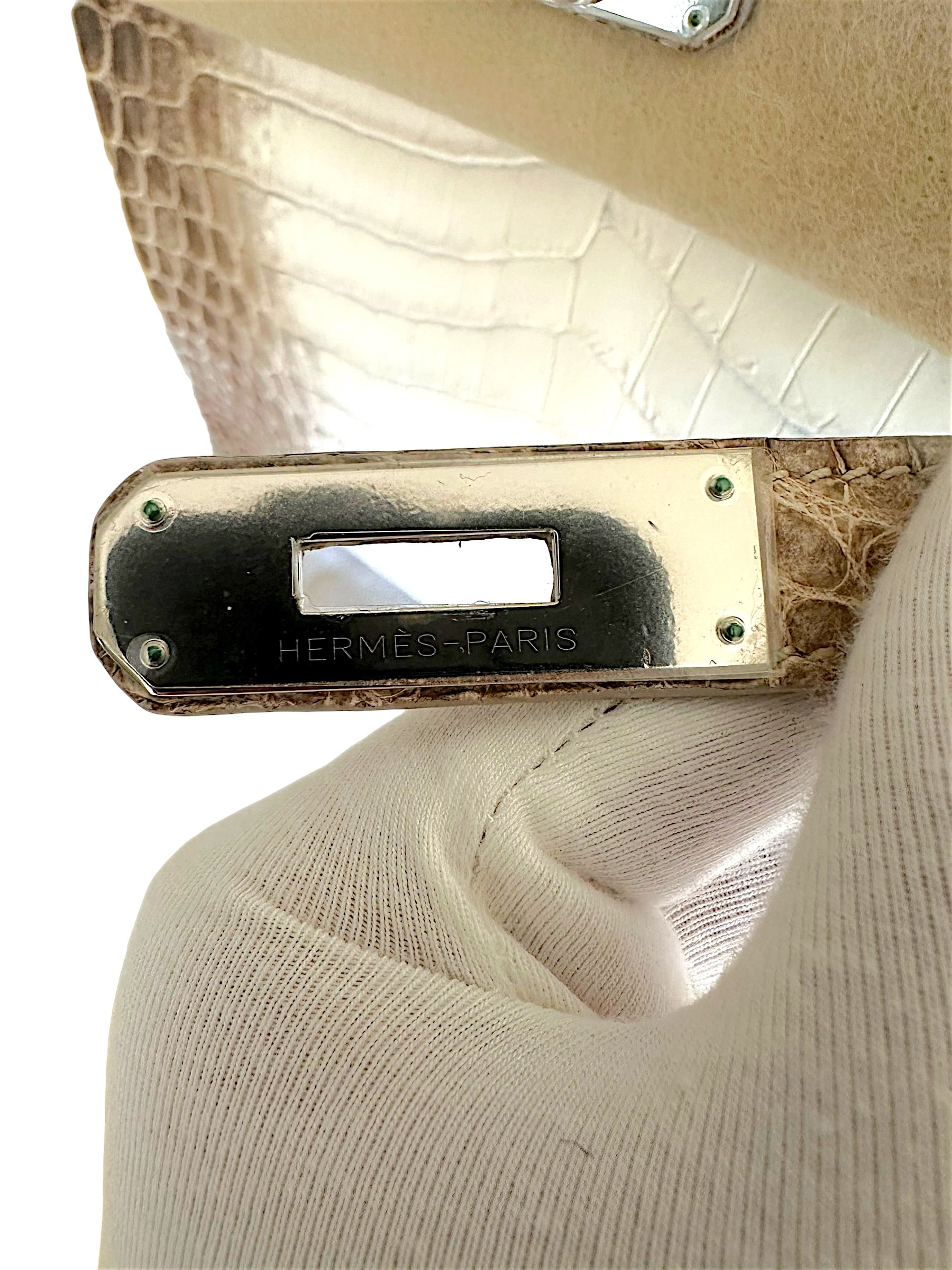 Close-up of Hermès Paris engraved palladium plaque hardware on Himalaya Niloticus Crocodile Birkin 30 with protective sticker intact.