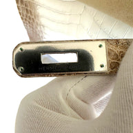 Close-up of Hermès Paris engraved palladium plaque hardware on Himalaya Niloticus Crocodile Birkin 30 with protective sticker intact.