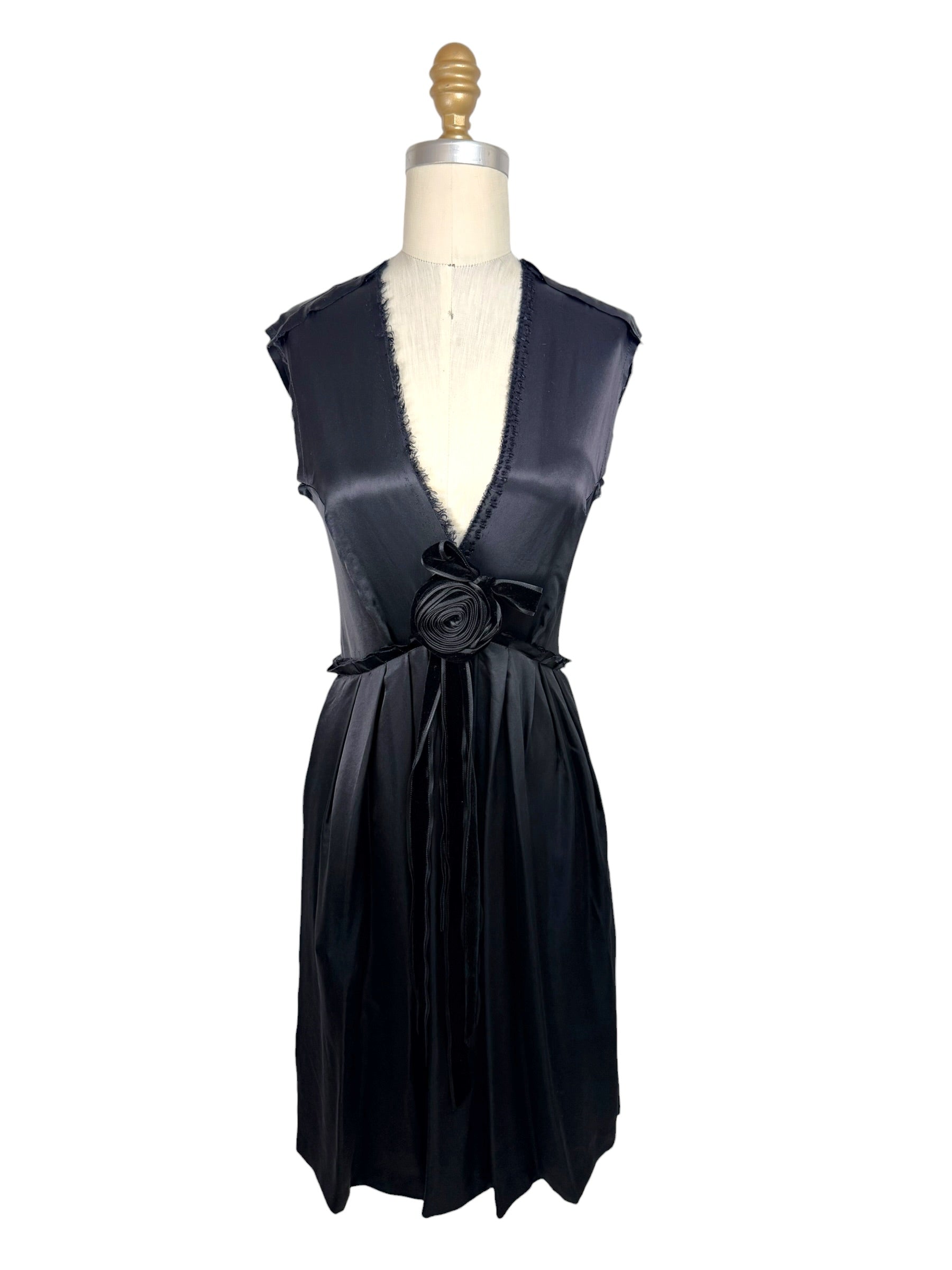 Front full view of Lanvin Hiver 2005 black satin sleeveless dress with plunging neckline, pleated skirt, and tonal rosette waist detail on mannequin.