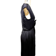Left side profile view of Lanvin Hiver 2005 black satin pleated dress with fluid silhouette and sleeveless construction.