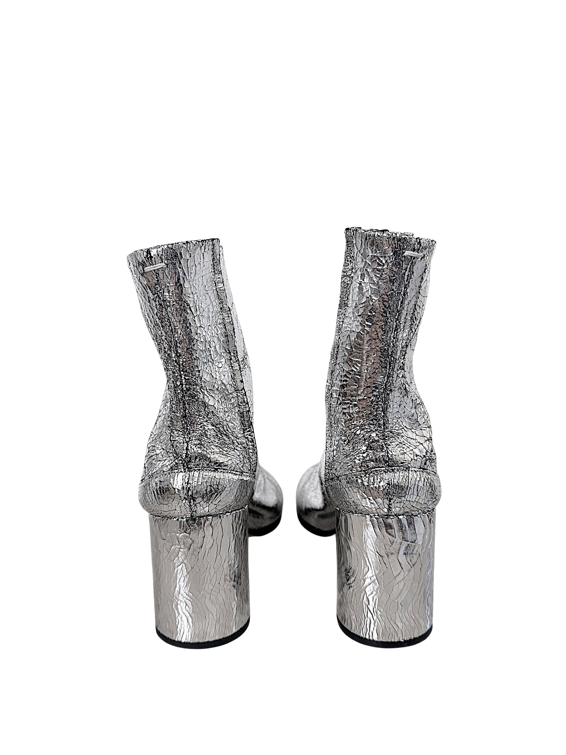 Rear view of Maison Margiela silver cracked leather Tabi ankle boots showing cylindrical block heels and signature white stitching
