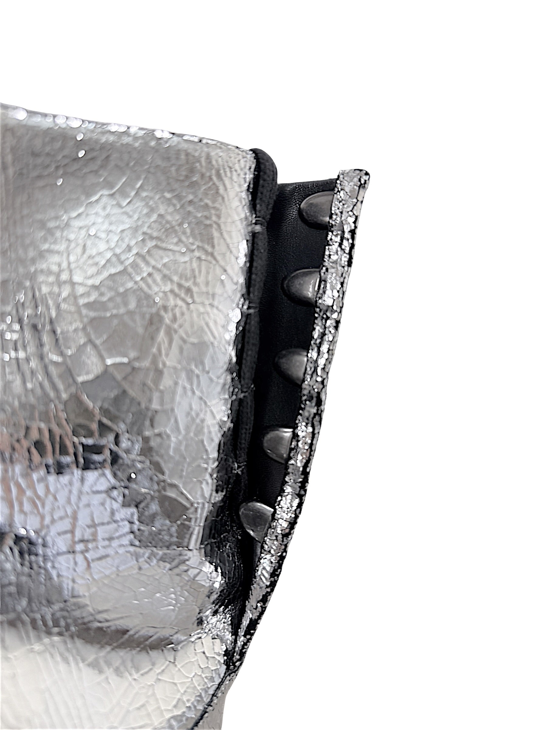 Close-up of Maison Margiela silver Tabi ankle boot showing concealed hook closure and intentional cracked metallic leather finish