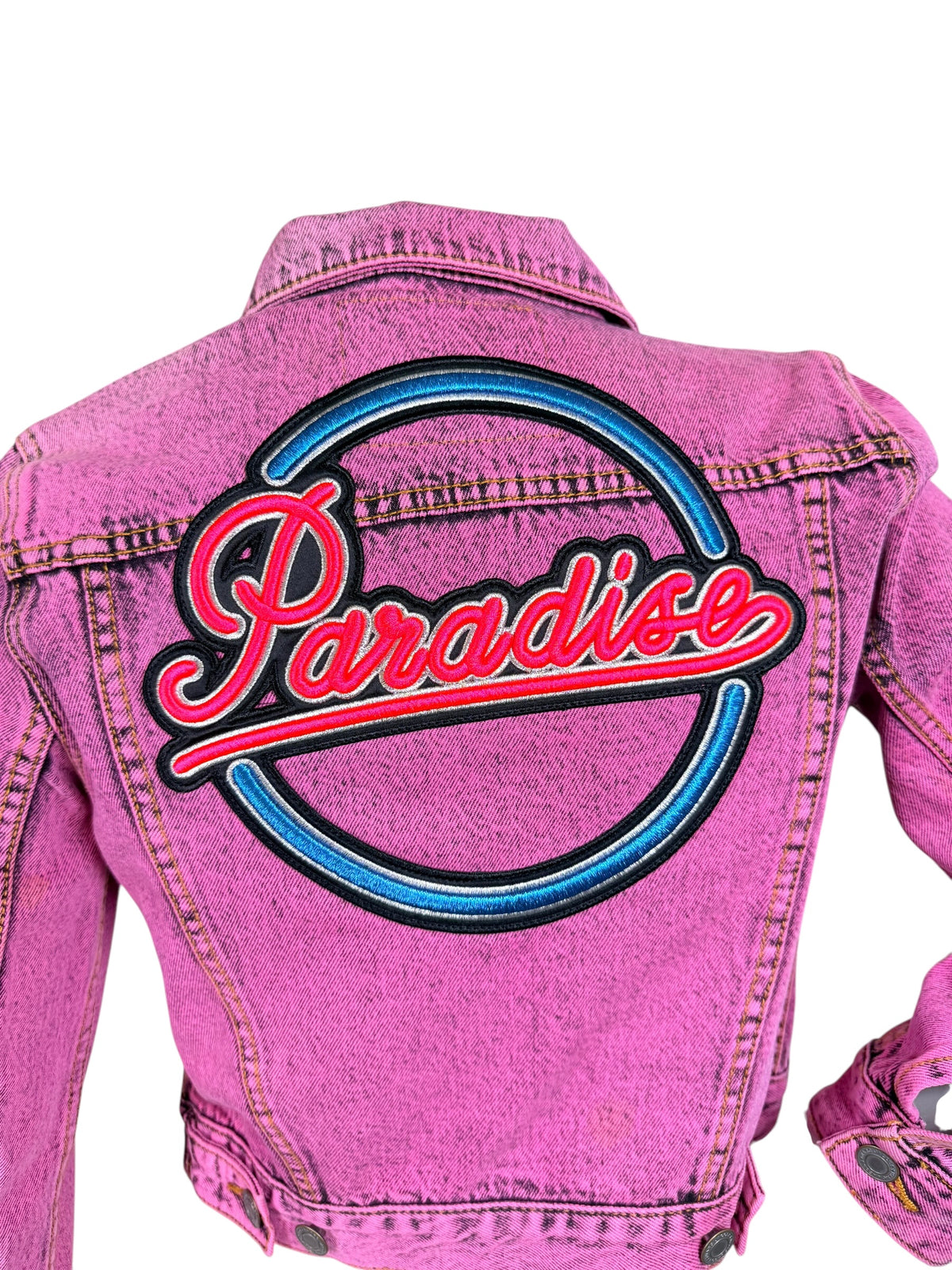 Close-up of oversized Paradise script embroidery in neon pink, blue and black across the back of a Marc Jacobs pink denim jacket.