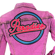 Close-up of oversized Paradise script embroidery in neon pink, blue and black across the back of a Marc Jacobs pink denim jacket.