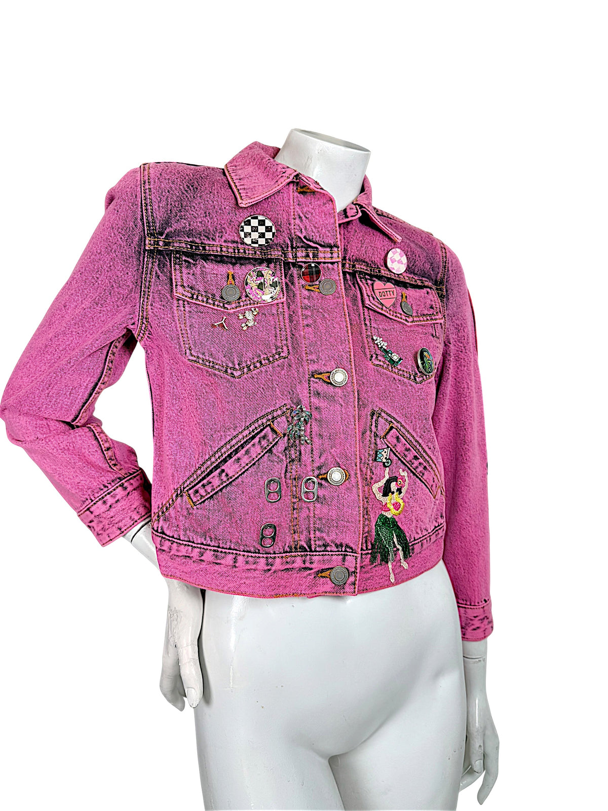 Angled front view of Marc Jacobs Paradise bright pink cropped denim jacket with black acid wash finish, embroidered patches and decorative pins.