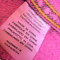 Close-up of Marc Jacobs Paradise pink denim jacket composition label confirming 100 percent cotton construction, made in China, and interior production codes.