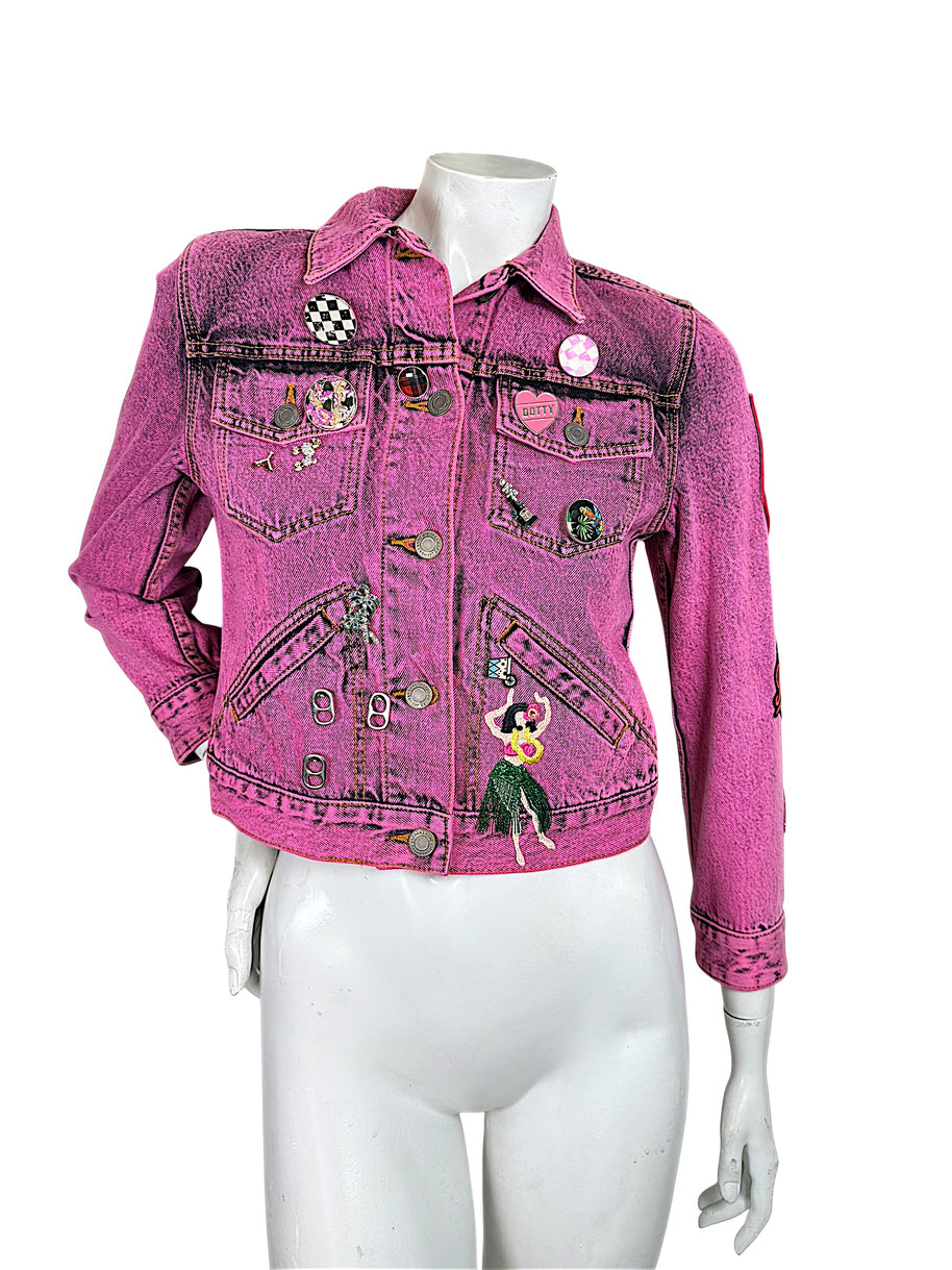 Front view of Marc Jacobs Paradise pink cropped denim jacket with button closure, novelty pins, chest pockets and colorful hula dancer embroidery.