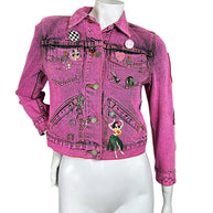 Front view of Marc Jacobs Paradise pink cropped denim jacket with button closure, novelty pins, chest pockets and colorful hula dancer embroidery.