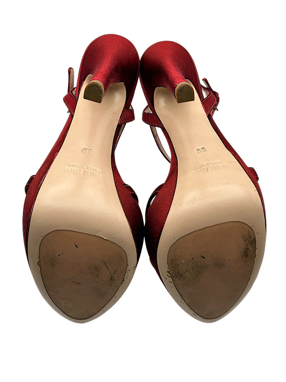 Underside of Miu Miu burgundy platform sandals showing leather outsoles with visible wear, heel tips and original designer markings.
